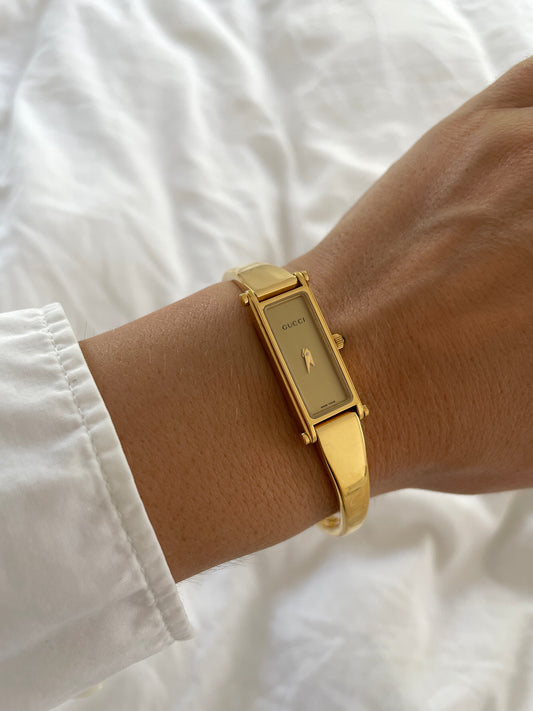 Vintage Gucci by Tom Ford 2000s 1500L 18K gold plated bangle watch with light golden dial and horsebit clasp.
