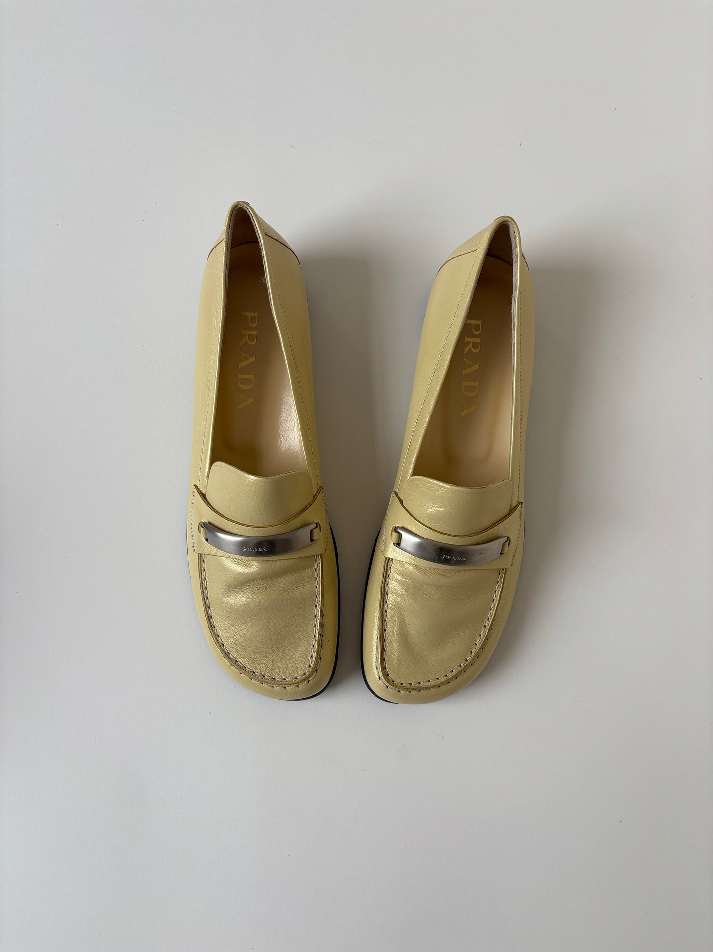 Vintage Prada 1990s pearly butter yellow loafer with metal logo detail.