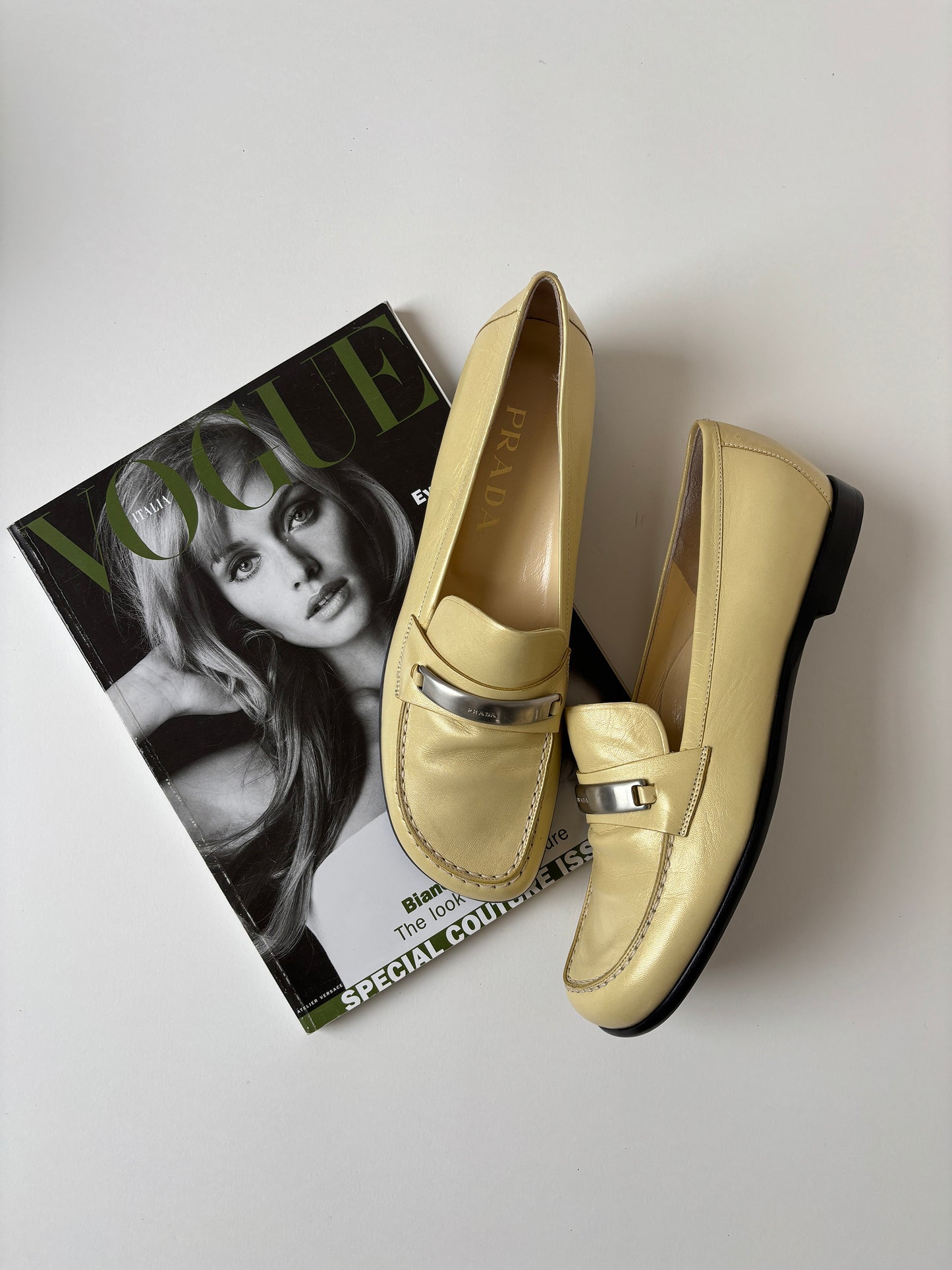 Vintage Prada 1990s pearly butter yellow loafer with metal logo detail.
