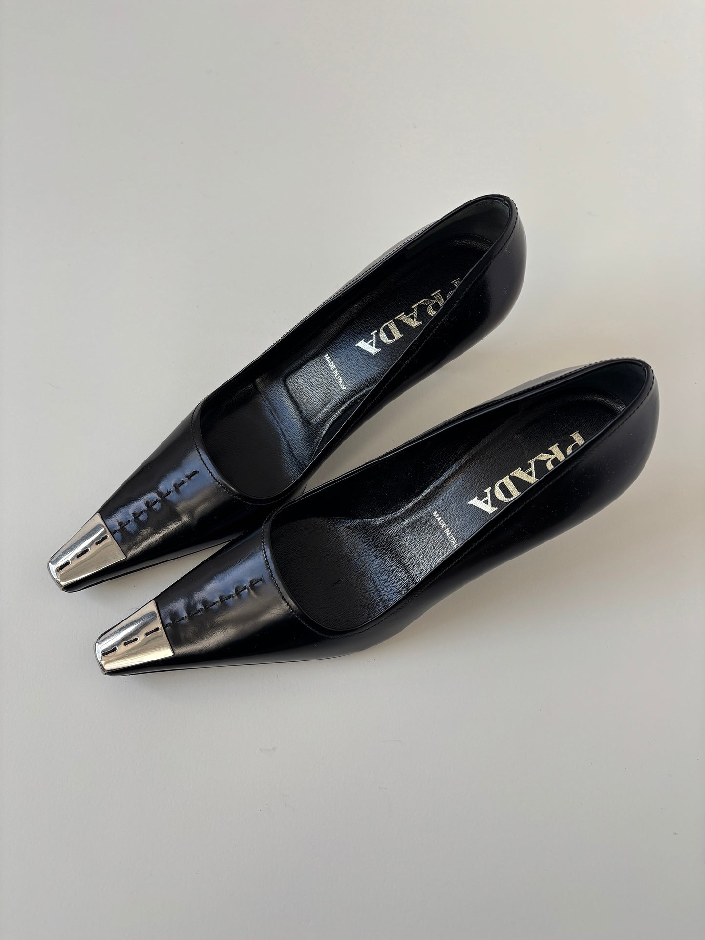 Vintage Prada 2000s black kitten heels with silver metal cap details.