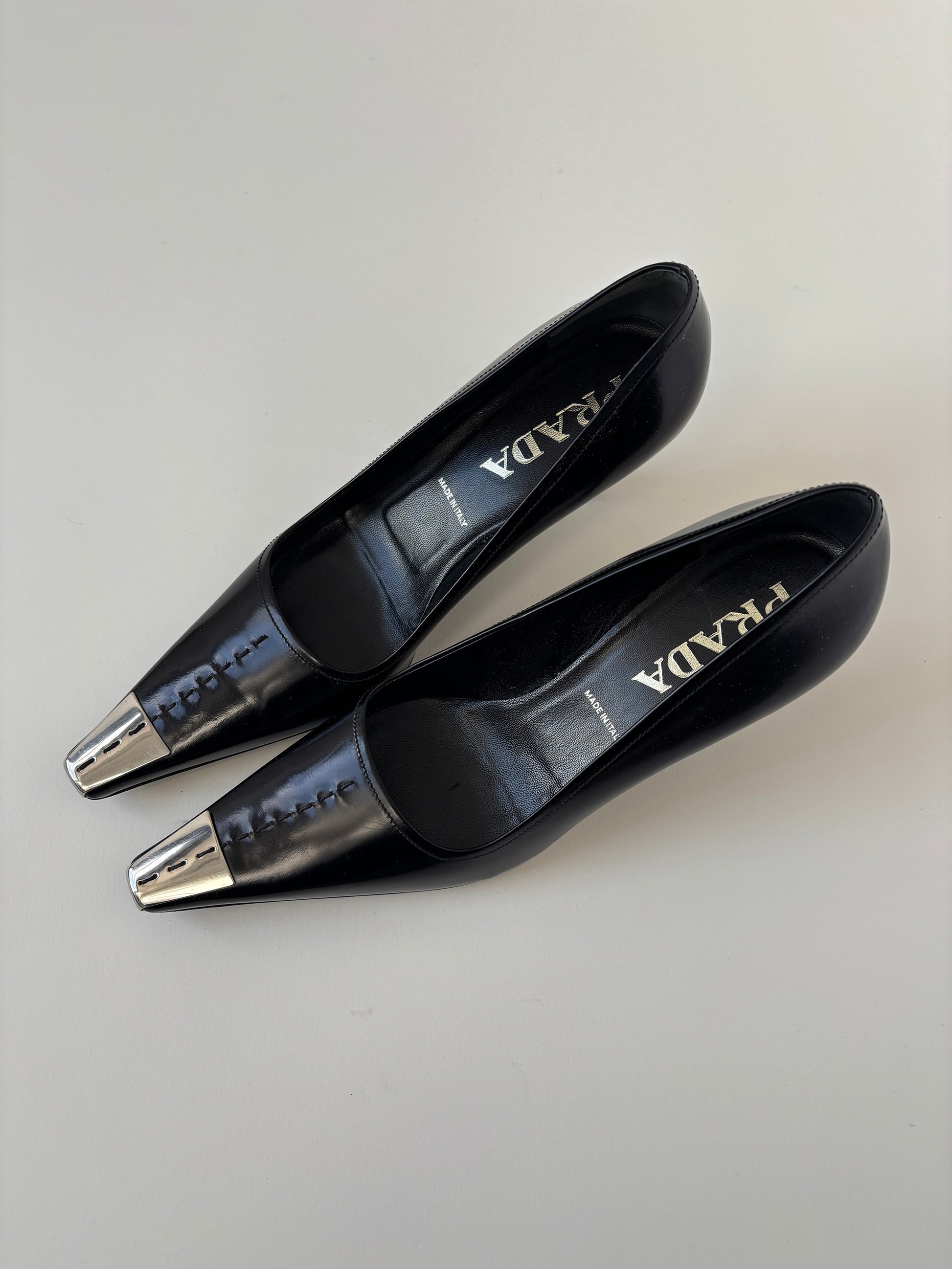 Vintage Prada 2000s black kitten heels with silver metal cap details.